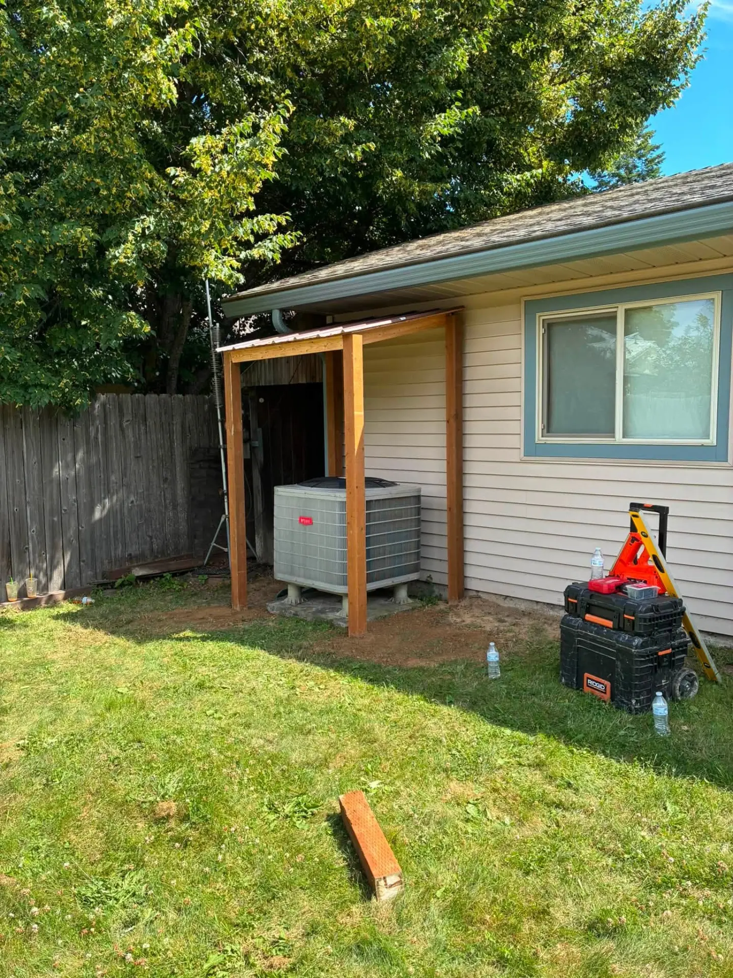 Custom-framed lean-to shelter built over a home air conditioning unit