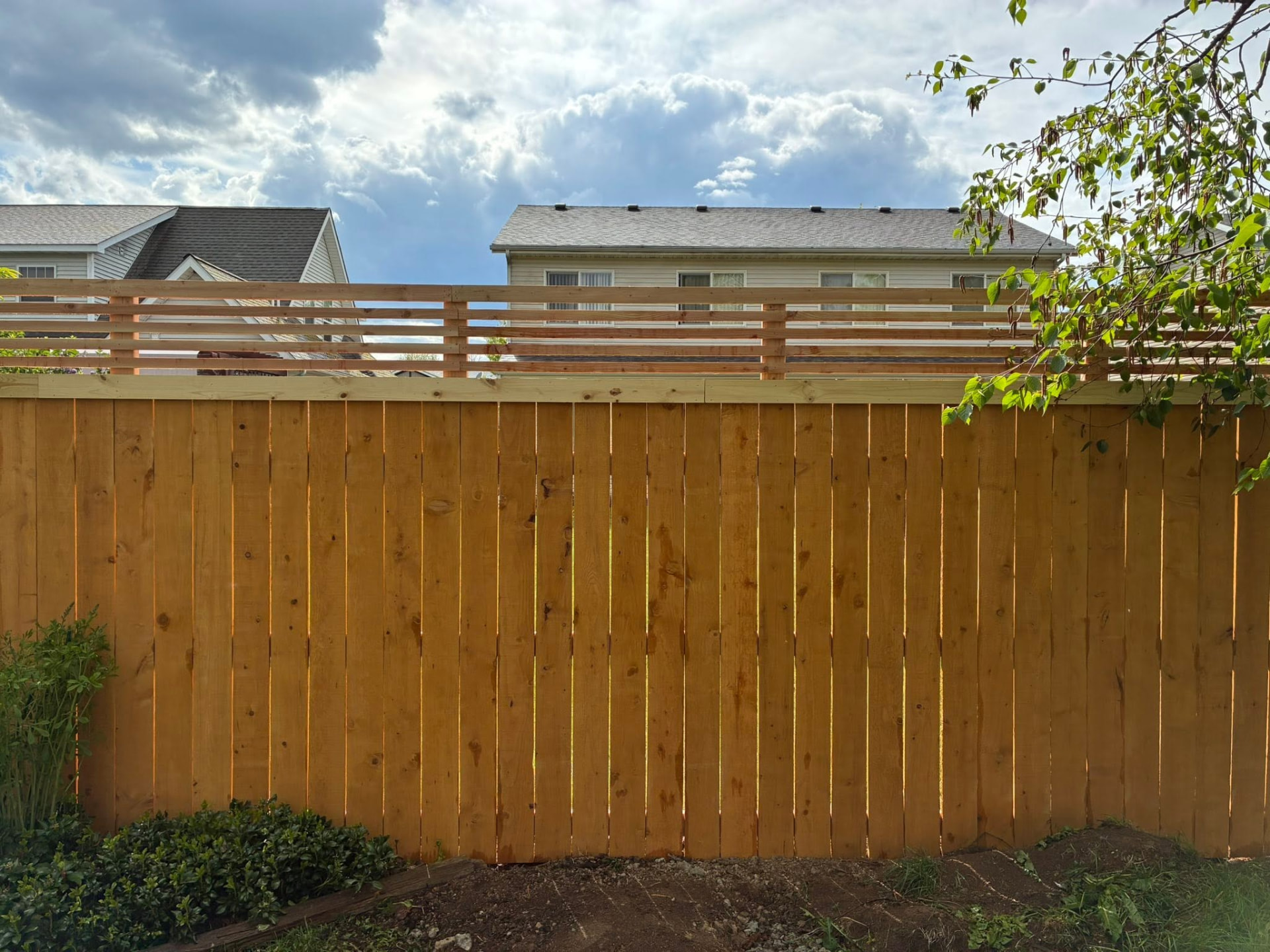 Newly built cedar privacy fence with horizontal slat topper